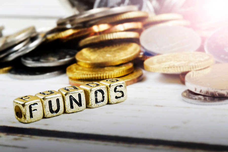 Dice with word FUNDS and coins on wooden background. Funding and business concept. Shallow DOF.